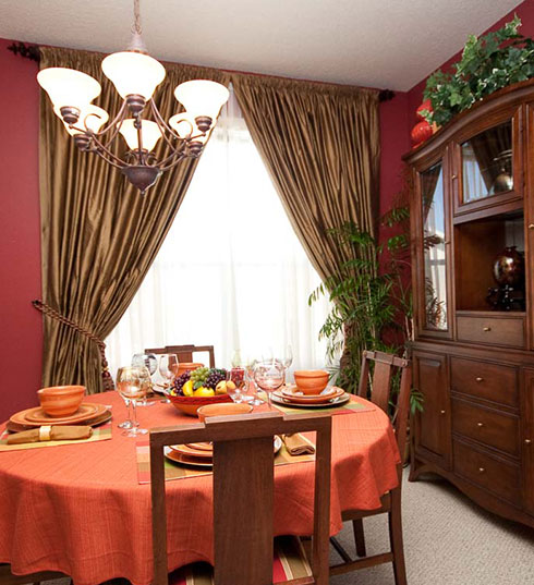 A dining room with a table and chairs, a bowl of fruit on the plate.