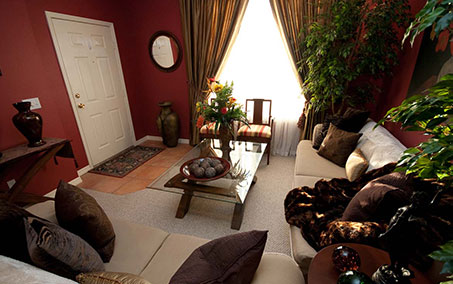 A living room with red walls and white furniture.