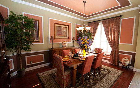 A dining room with a table and chairs, and a vase of flowers.