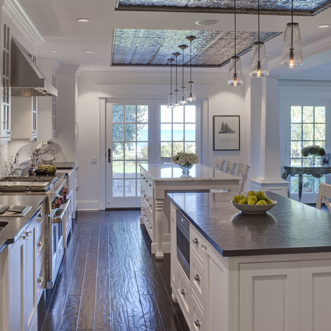 A kitchen with white cabinets and wooden floors