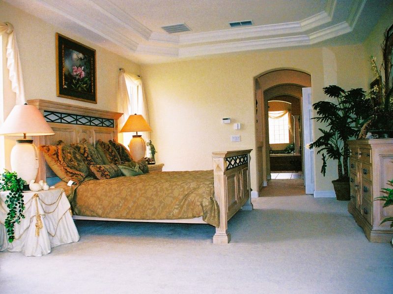 A bedroom with a bed, chair and lamp.