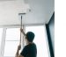 A man is painting the ceiling of his home.